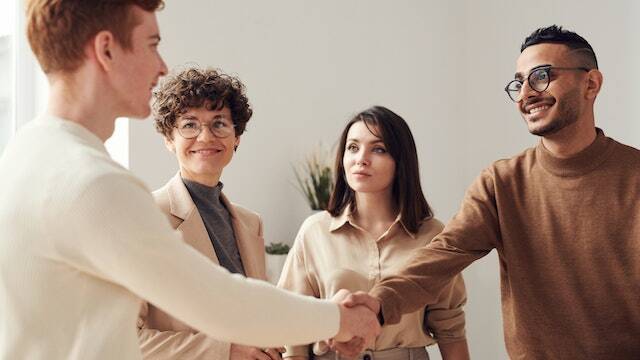 two people shaking hands while two other watch and smile